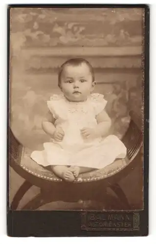 Fotografie N. Baumann, Altomünster, hübsches Baby in Spitzenkleidchen auf Hocker sitzend