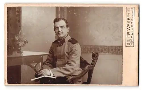 Fotografie Fr. Wäger, Altona, Portrait Soldat in Uniform mit Zeitschrift auf Stuhl sitzend