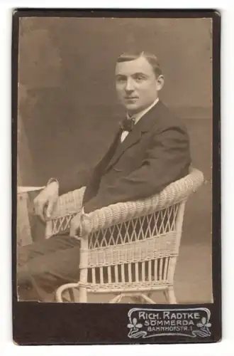 Fotografie Rich. Radtke, Sömmerda, Portrait charmanter Herr mit Fliege im Anzug im Korbstuhl sitzend