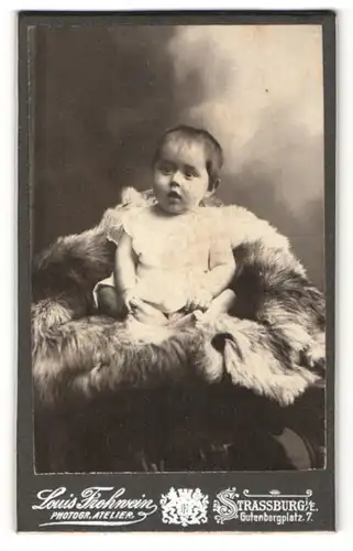 Fotografie Louis Frohwein, Strassburg i. E., staunendes Baby auf Felldecke sitzend