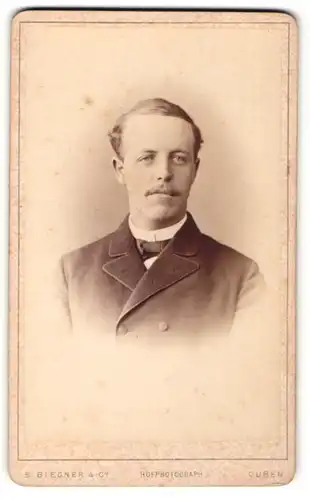 Fotografie E. Biegner & Co., Guben, Portrait charmanter Herr mit Oberlippenbart u. Fliege im Anzug