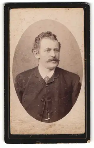 Fotografie C. Weidinger, Linz, Portrait charmant blickender Herr mit lockigem Haar und Schnurrbart