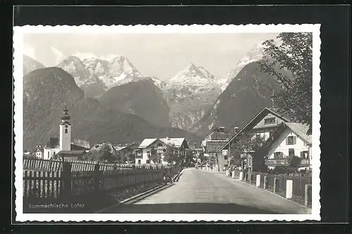 AK Lofer, Teilansicht mit Strasse und Häuserfassaden mit Kirchturm und Blick auf Gebirge