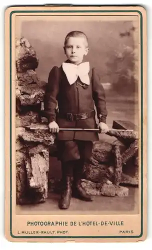 Fotografie L. Muller-Rault, Paris, Junge in Anzug mit Schleife u. Gürtel, Gerte in Hand