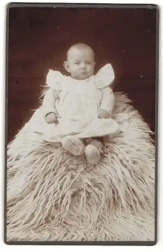 Fotografie Fotograf & Ort unbekannt, Portrait niedliches Baby mit dicken Wangen auf Felldecke