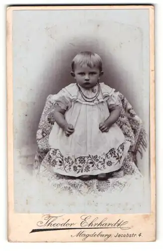 Fotografie Theodor Ehrhardt, Magdeburg, Portrait niedliches Kleinkind im hübschen Kleid auf Stuhl stehend