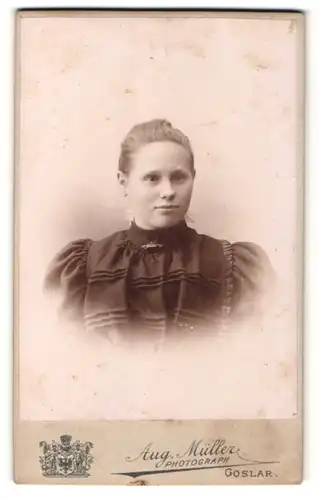 Fotografie Aug. Müller, Goslar, Portrait junge Dame mit zurückgebundenem Haar im eleganten Kleid