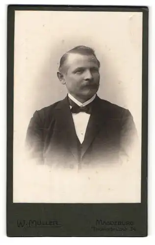 Fotografie W. Müller, Magdeburg, Portrait charmanter Herr mit Schnauzbart u. Fliege im Anzug