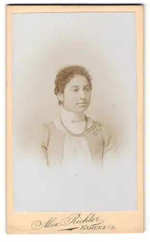 Fotografie Alex. Richter, Kamenz i. Sa., Portrait brünette junge Frau mit lockigem Haar und Perlenhalskette