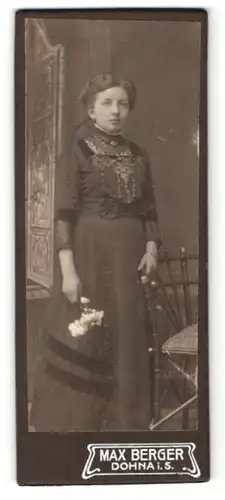 Fotografie Max Berger, Dohna i. S., Portrait bezaubernde Dame mit Blumen im prachtvoll besticktem Kleid
