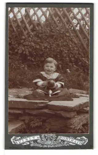 Fotografie unbekannter Fotograf und Ort, Visit-Portrait niedliches Kleinkind mit Ball auf Steinen sitzend