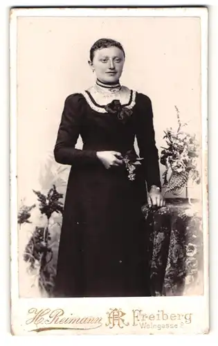 Fotografie H. Reimann, Freiberg, Portrait dunkelhaariges hübsches Fräulein mit Blumen und Schleife