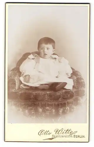 Fotografie Otto Witte, Berlin, Portrait niedliches Kleinkind im weissen Kleid auf Sessel sitzend