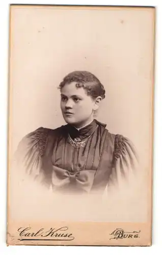 Fotografie Carl Kruse, Burg, Portrait junge Dame mit zurückgebundenem Haar in elegantem Kleid