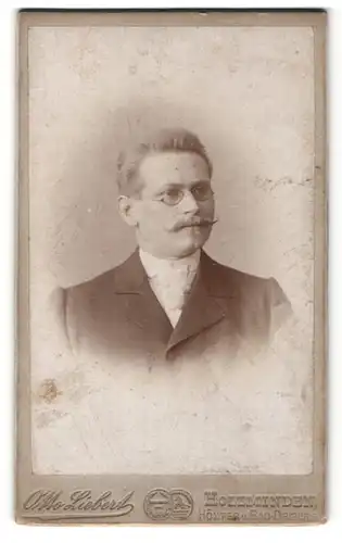 Fotografie Otto Liebert, Holzminden, Höxter & Bad-Driburg, Portrait charmanter Herr mit Brille u. Zwirbelbart im Anzug