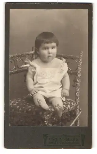 Fotografie C. Schmid-Dubied, Basel, Baby auf Stuhl im Foto-Atelier sitzend