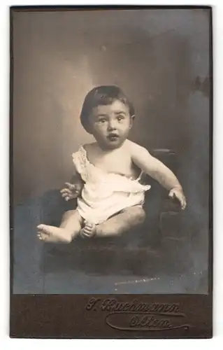Fotografie J. Buchmann, Olten, Portrait niedliches Kleinkind im weissen Hemd auf Sessel sitzend