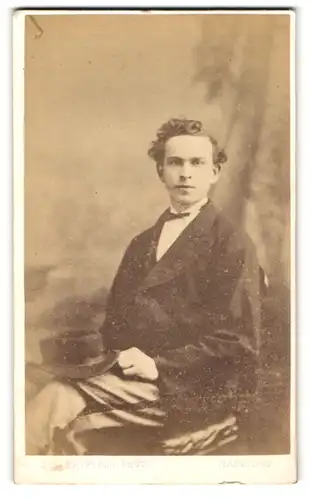 Fotografie J.S. Bayfield, Hastings, Junger Mann mit Hut in einem Stuhl sitzend