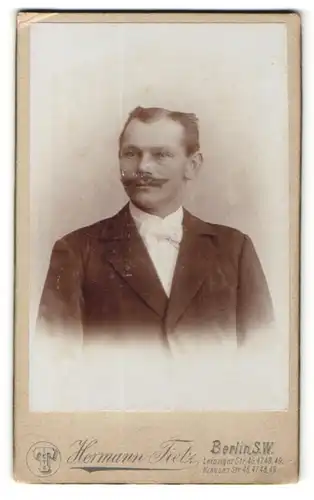 Fotografie Hermann Tietz, Berlin, Portrait charmant blickender Herr mit Schnurrbart und weisser Fliege im Jackett