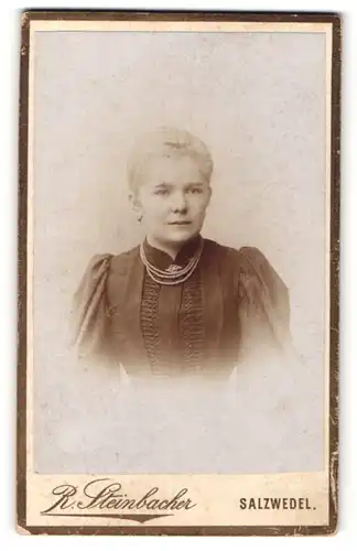 Fotografie R. Steinbacher, Salzwedel, Elegante Dame in dunklem Kleid mit Perlenkette