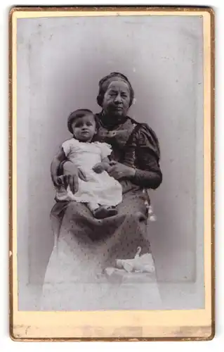 Fotografie unbekannter Fotograf und Ort, Portrait ältere Dame im zeitgenöss. Kleid mit Kind im Arm