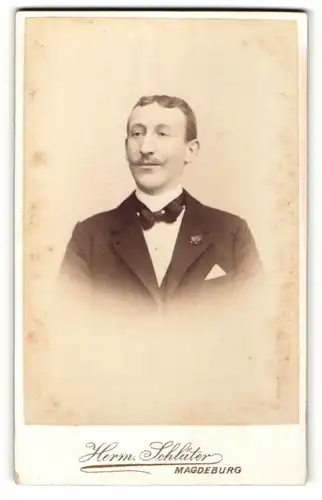Fotografie Herm. Schlüter, Magdeburg, Portrait charmanter Herr mit Fliege im Anzug