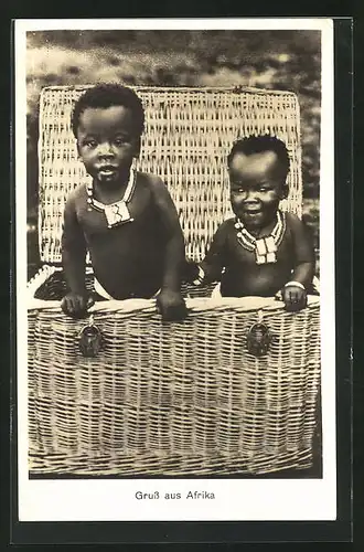 AK Afrikanische Kleinkinder blicken aus einem grossen Korb, afrikanische Volkstypen