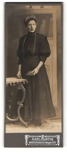 Fotografie Karl Hurtig, Wilhelmshaven, Dame in Bluse mit Puffärmeln und ein Buch haltend
