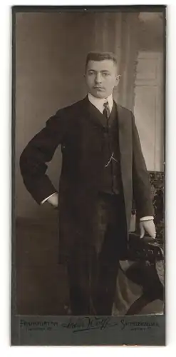 Fotografie Atelier Wolff, Frankfurt a. M., Sachsenhausen, Portrait charmanter Herr im Anzug an Stuhl gelehnt