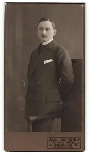 Fotografie Ad. Junghans Nachf., Magdeburg-Neustadt, Portrait charmanter Herr im Anzug an Lehne stehend