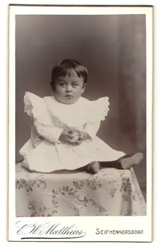 Fotografie E. W. Matthias, Seifhennersdorf, Portrait niedliches kleines Mädchen mit Ball im weissen Kleidchen