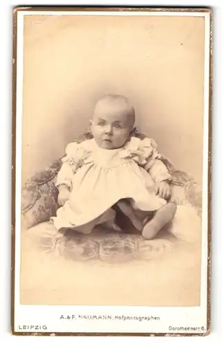 Fotografie A. & F. Naumann, Leipzig, Portrait bezauberndes Baby im weissen Kleidchen mit Schleifen an den Schultern