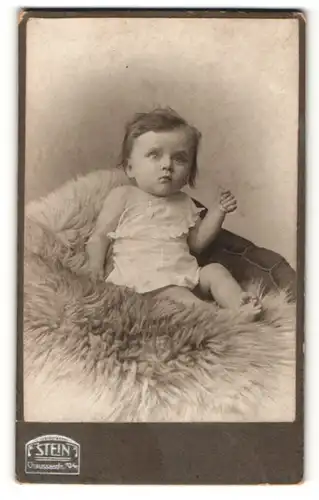 Fotografie Atelier Stein, Berlin, Portrait niedliches Kleinkind im weissen Hemd auf Fell sitzend