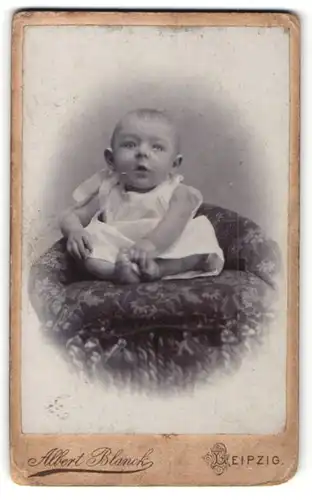 Fotografie Albert Blanck, Leipzig, Portrait niedlichs Baby im weissen Hemd auf Sessel sitzend