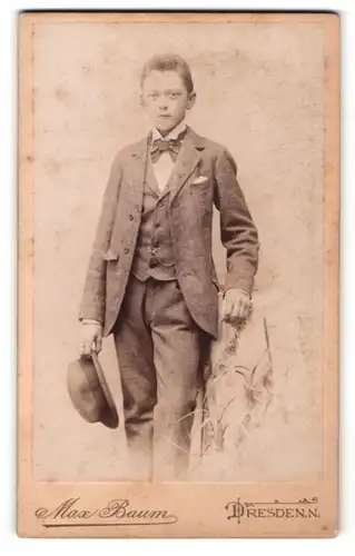 Fotografie Max Baum, Dresden-N, Portrait junger Herr im Anzug mit Hut an Tisch gelehnt