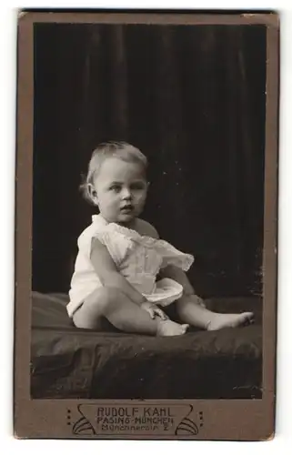 Fotografie Rudolf Kahl, Pasing-München, Portrait niedliches Kleinkind im weissen Hemd auf Laken sitzend