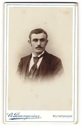 Fotografie Ch. Baumgartner, Wolfrathshausen, Portrait junger Herr mit Oberlippenbart in Anzug mit Krawatte