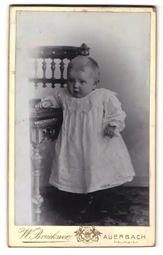 Fotografie W. Bruckner, Auerbach, Portrait süsses blondes Kleinkind im weissen Kleidchen