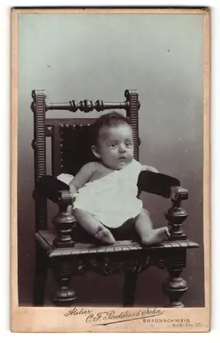 Fotografie Atelier C. F. Beddies & Sohn, Braunschweig, Säugling auf einem hölzernen Stuhl
