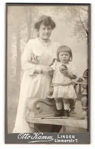 Fotografie Otto Kamm, Linden, Portrait kleines Mädchen mit Ball auf Bank stehend u. lächelnde Mutter