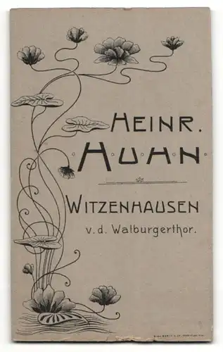Fotografie Heinr. Huhn, Witzenhausen, Portrait niedliches Kleinkind im karierten Kleid auf Fell sitzend