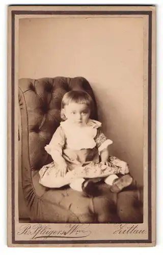 Fotografie R. Pflügers Witwe, Zittau, Portrait kleines Mädchen im hübschen Kleid auf Sessel sitzend