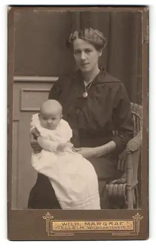 Fotografie Wilh. Margraf, Celle i. H., Portrait lächelnde Mutter auf Stuhl sitzend mit Baby im Arm