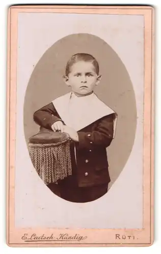 Fotografie E. Laetsch-Kündig, Rüti, Portrait kleiner Junge im Matrosenanzug auf Lehne gestützt