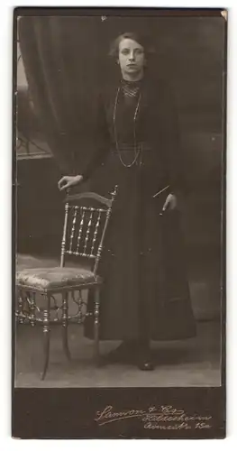 Fotografie Samson & Co, Hildesheim, Portrait dunkelhaarige junge Frau mit Buch im dunklen Kleid