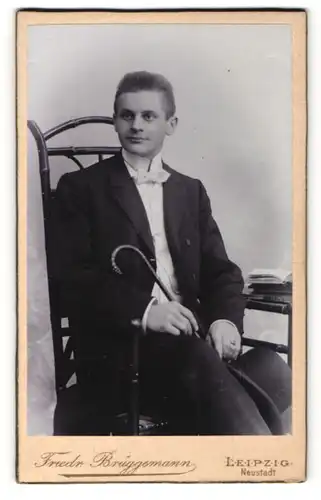 Fotografie Friedr. Brüggemann, Leipzig, Portrait charmant blickender junger Mann mit Gehstock