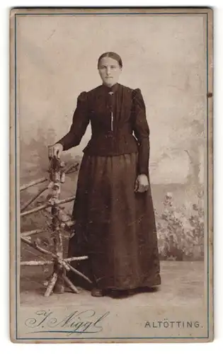 Fotografie J. Niggl, Altötting, Portrait brügerliche Dame in eleganter Kleidung an Zaun gelehnt