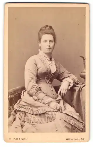 Fotografie C. Brasch, Berlin-W, Portrait junge Dame im eleganten Kleid am Tisch sitzend