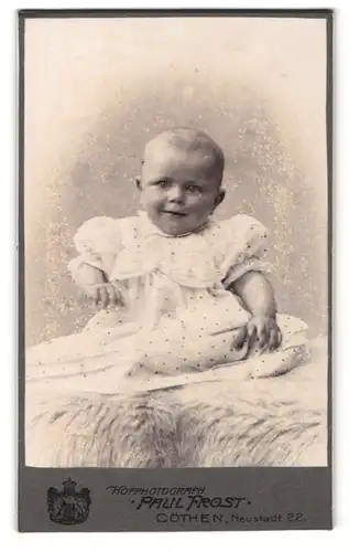 Fotografie Paul Frost, Cöthen, Portrait lächelndes niedliches Baby im gepunkteten Kleidchen