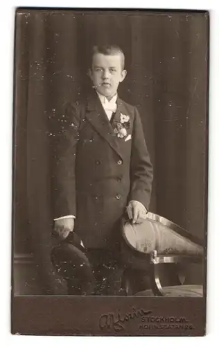 Fotografie A. Florin, Stockholm, Portrait junger Herr im Anzug mit Schirmmütze an Stuhl gelehnt